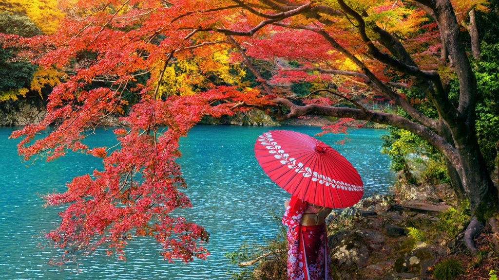 Best Time to Visit Japan: Asian woman wearing Japanese traditional kimono at Arashiyama in autumn season along the river in Kyoto, Japan.