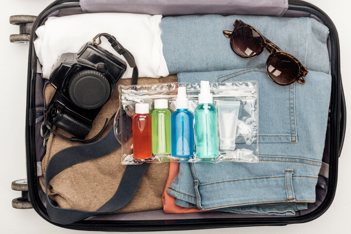 Fun Weekend Trip in Your State: travel bag with towel, cosmetic bag with colorful bottles, digital camera, clothes and sunglasses