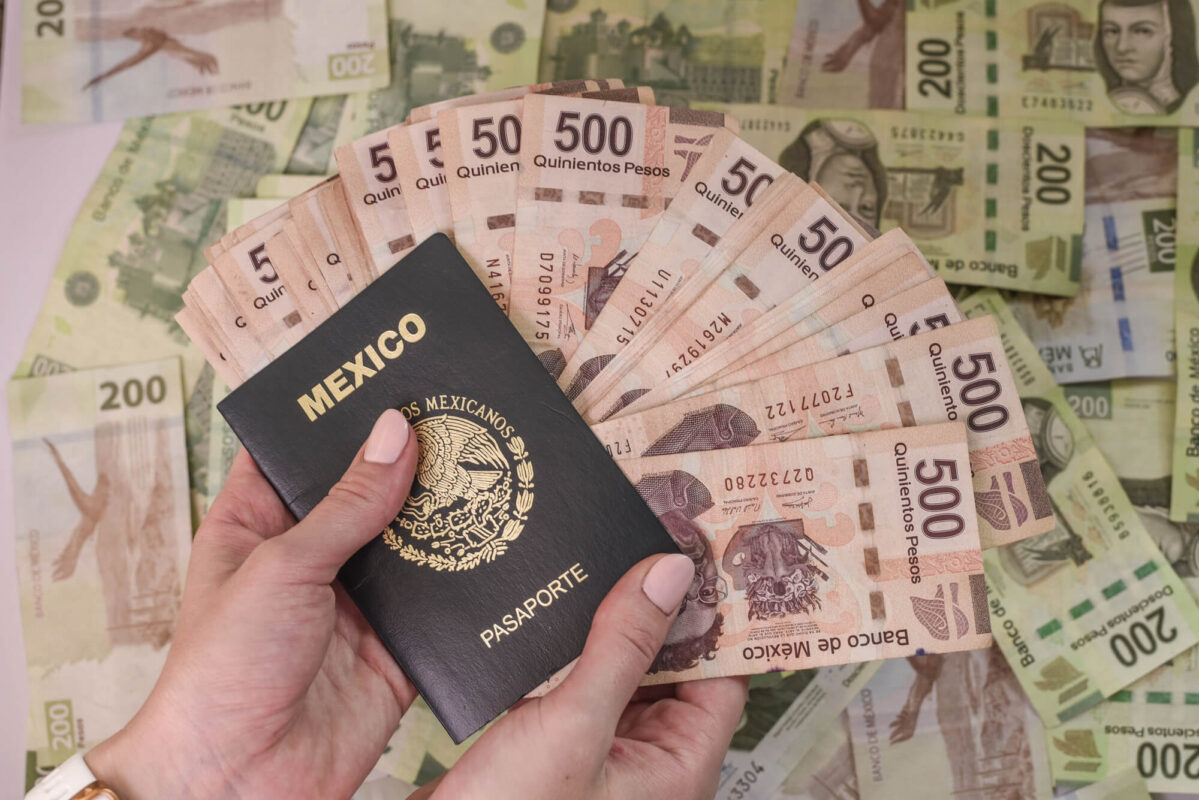 A closeup shot of female hands holding a Mexican passport and five hundred peso banknotes