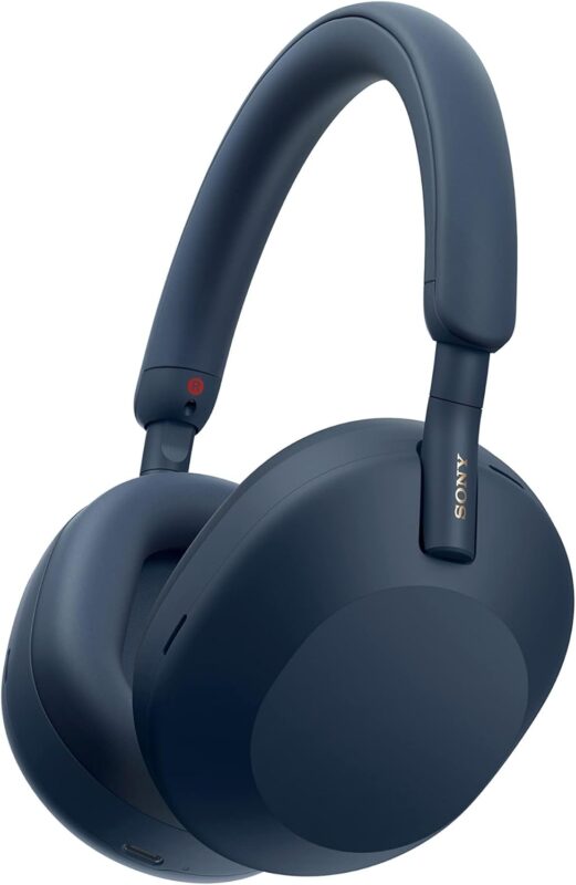A high-quality product shot of the Sony WH-1000XM5 wireless noise-canceling headphones in a dark blue color. The headphones are shown at a slight angle on a white background, highlighting their sleek, over-ear design. This popular model is often considered one of the best travel gadgets for its superior sound and comfort.