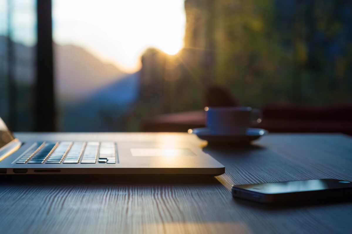 Computer Coffee Mug and Telephone on black wood table sun rising
