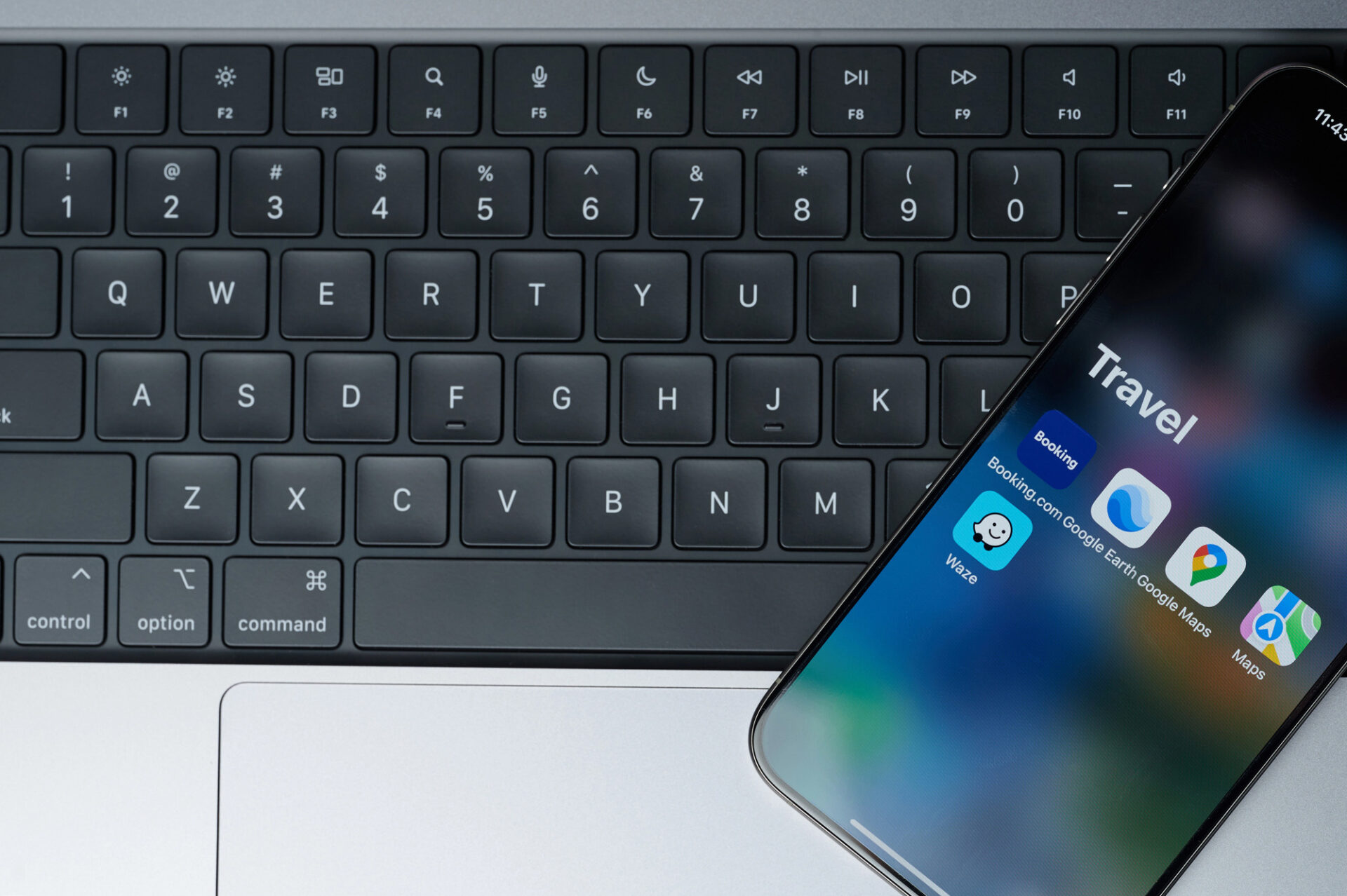 Iphone smartphone screen with keyboard background displaying some of the best travel apps.