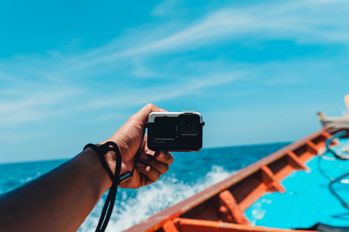 Man holding a travel action camrera traveling on a long-tail boat on the bay at Koh Tao,thailand